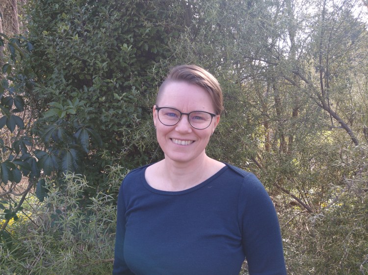 Deborah wearing a blue top and round glasses