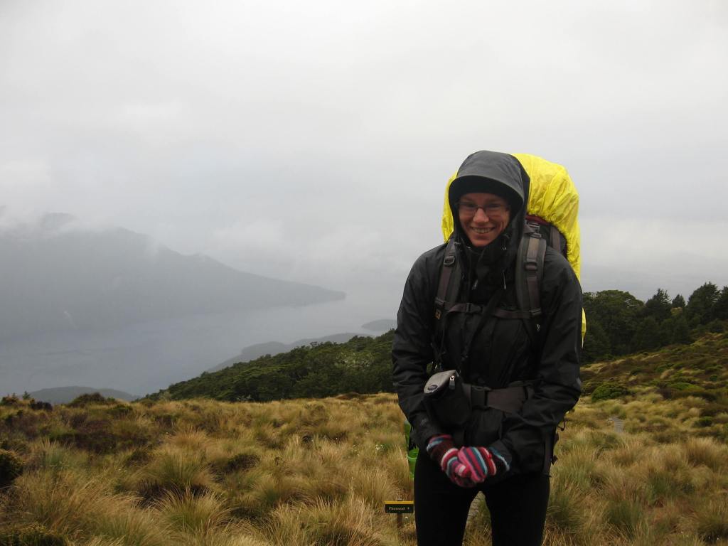 Deborah huddles in a rain jacket. The background is misty and rainy.