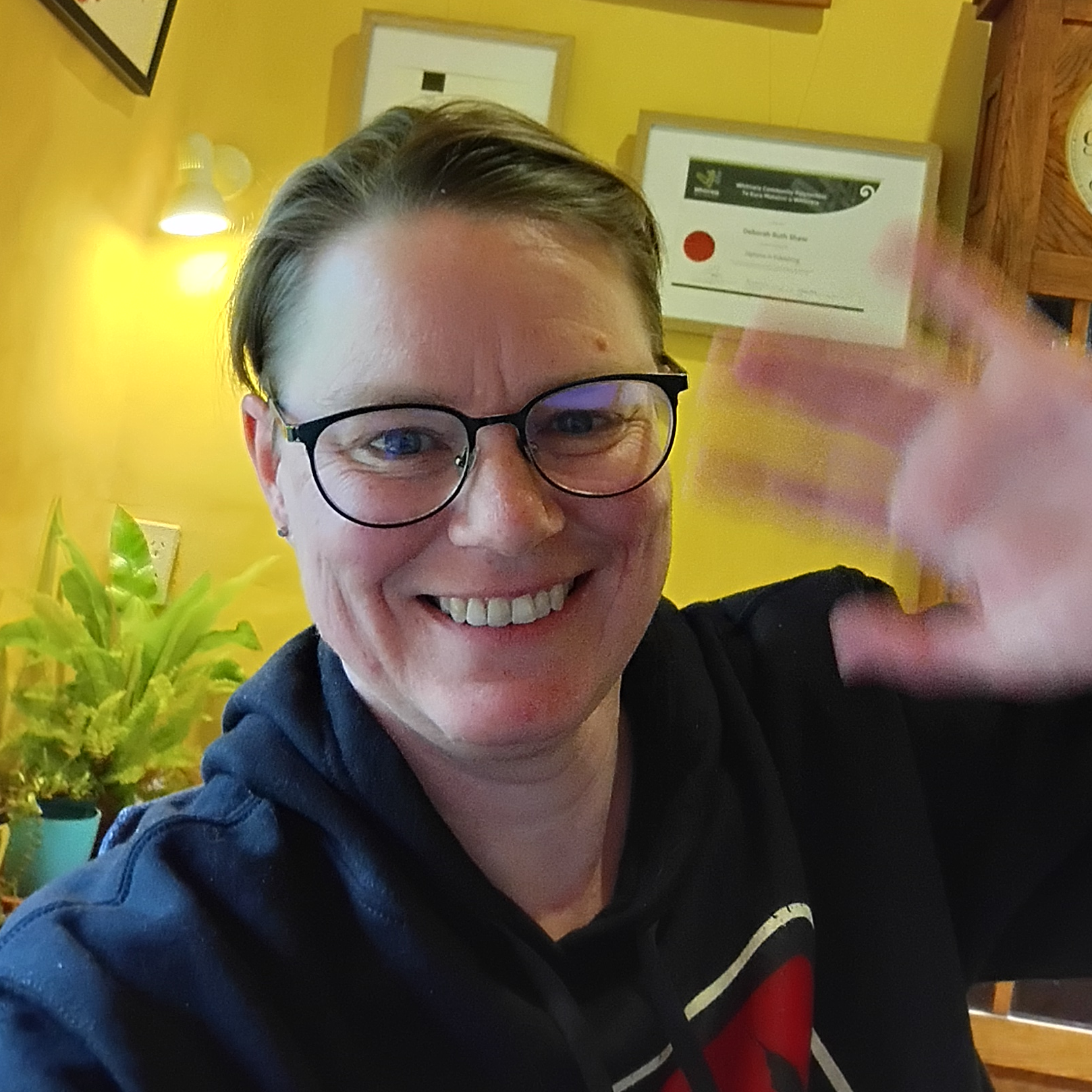 Deborah smiles and waves at the camera